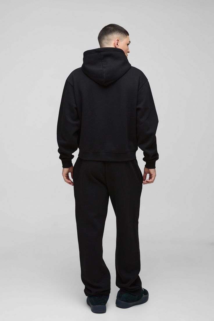 Person wearing a black hoodie and pants on a gray background
